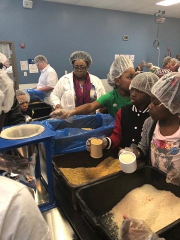Volunteers in hairnet packeting wheat and rice